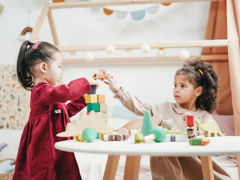 Two preschool children building with wooden blocks in a bright early learning room