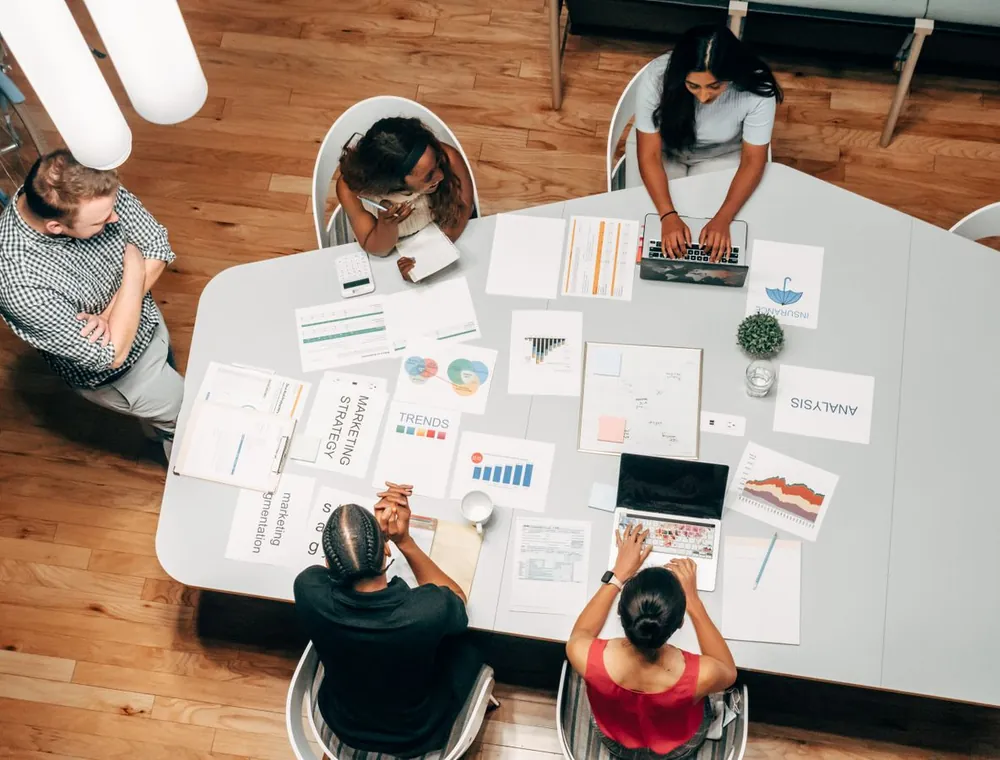 Marketing team reviewing SEO strategy, analytics and campaign documents around a table